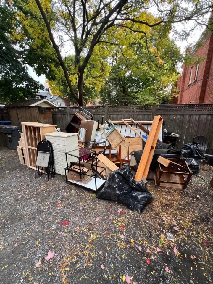 Dressers, shelves, a bed frame and bags piled outside for pickup